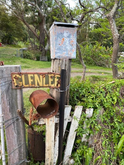 Weathered GLENLEE entrance sign and mailbox on a post